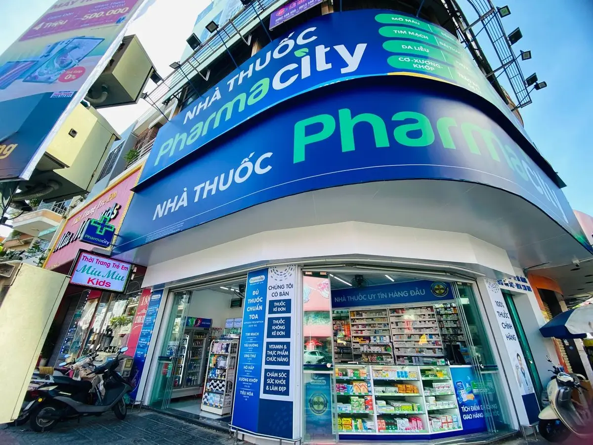 Pharmacity薬局の角の店舗。「Nha Thuoc Pharmacity」と書かれた大きな青い看板と、店内に通じるガラスの扉がある。