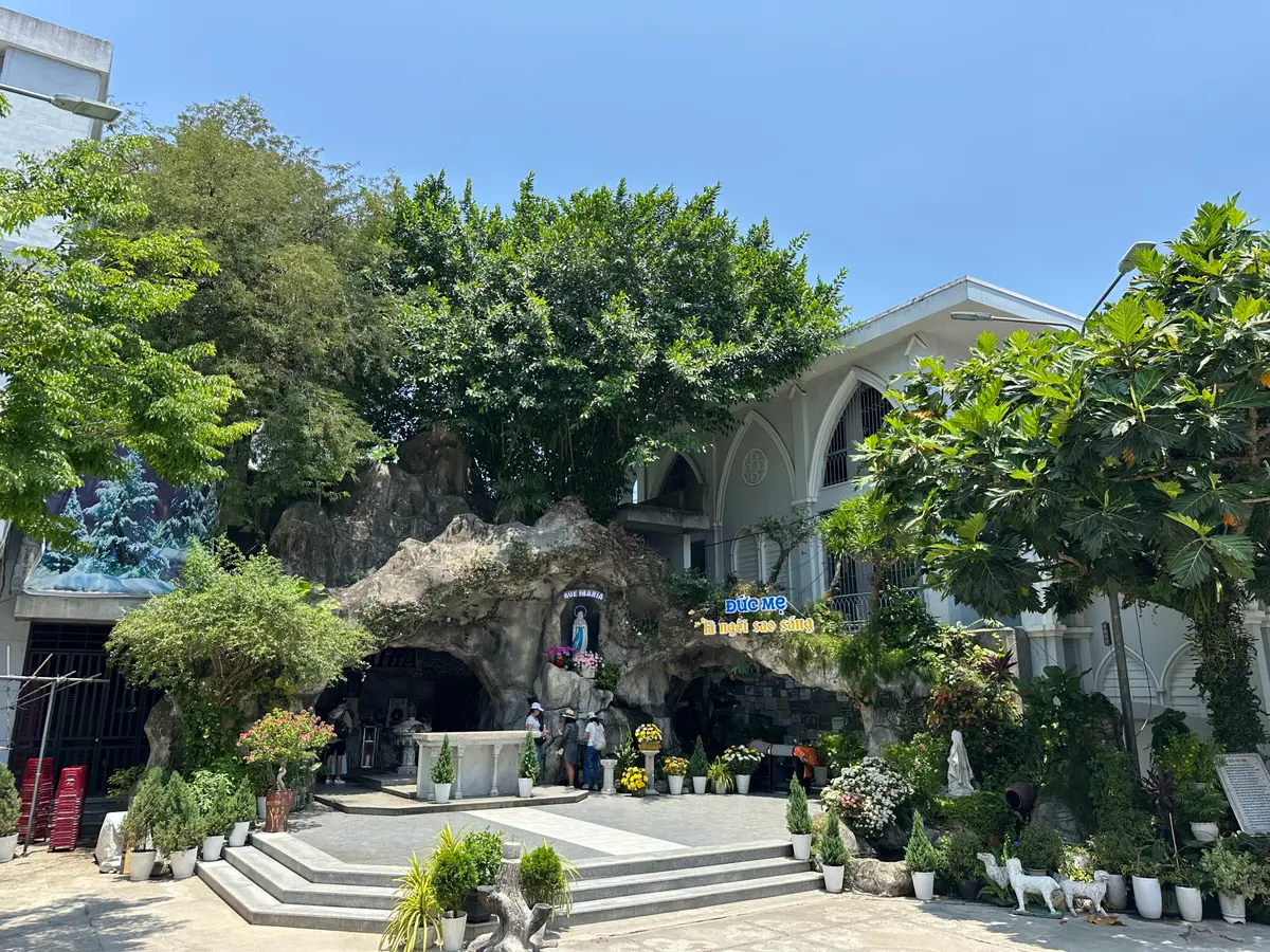 The garden courtyard behind the cathedral with a rock grotto, potted plants and steps.
