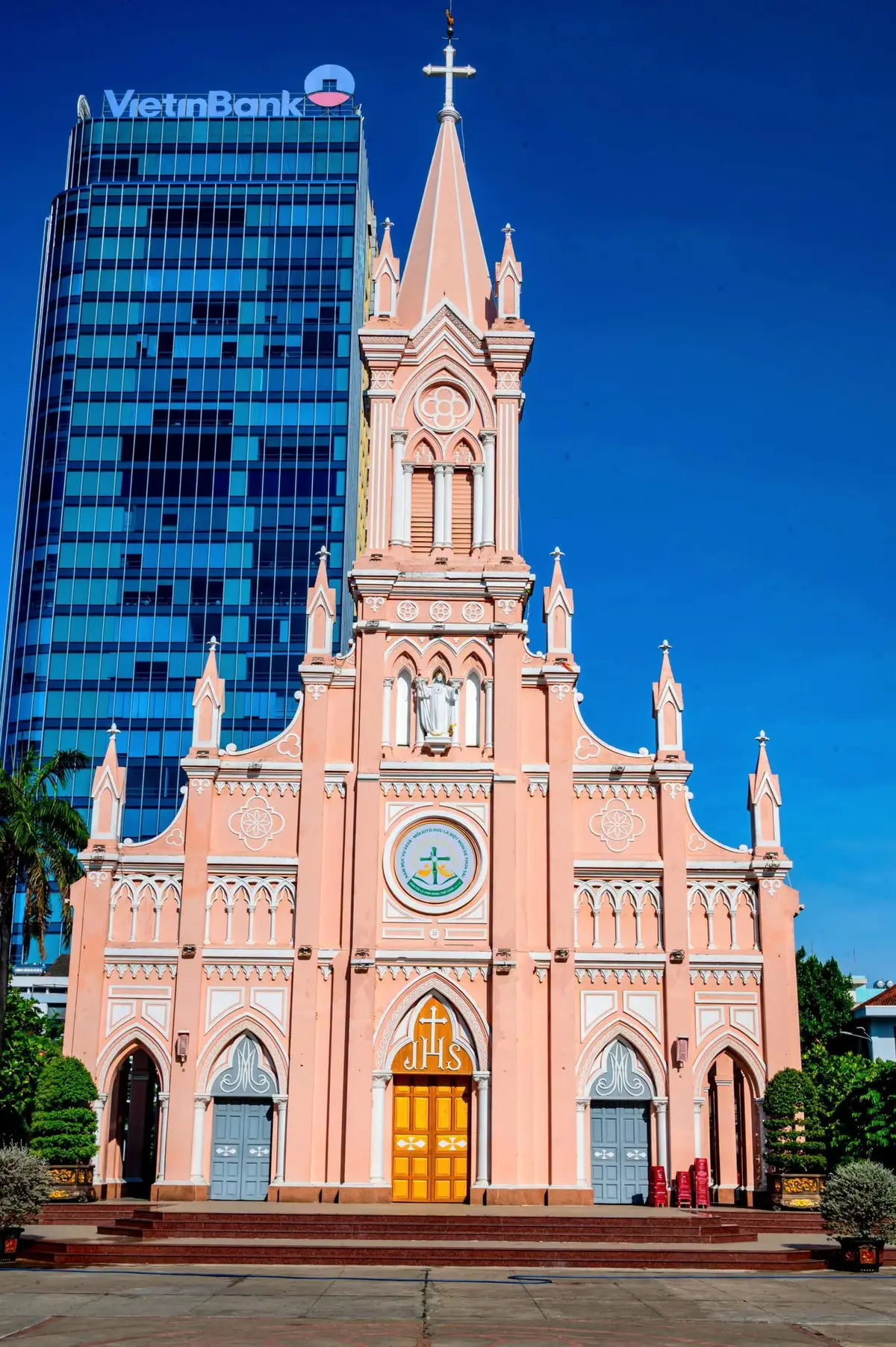 Close view of the cathedral's pink facade, clock and bell tower against a blue sky.