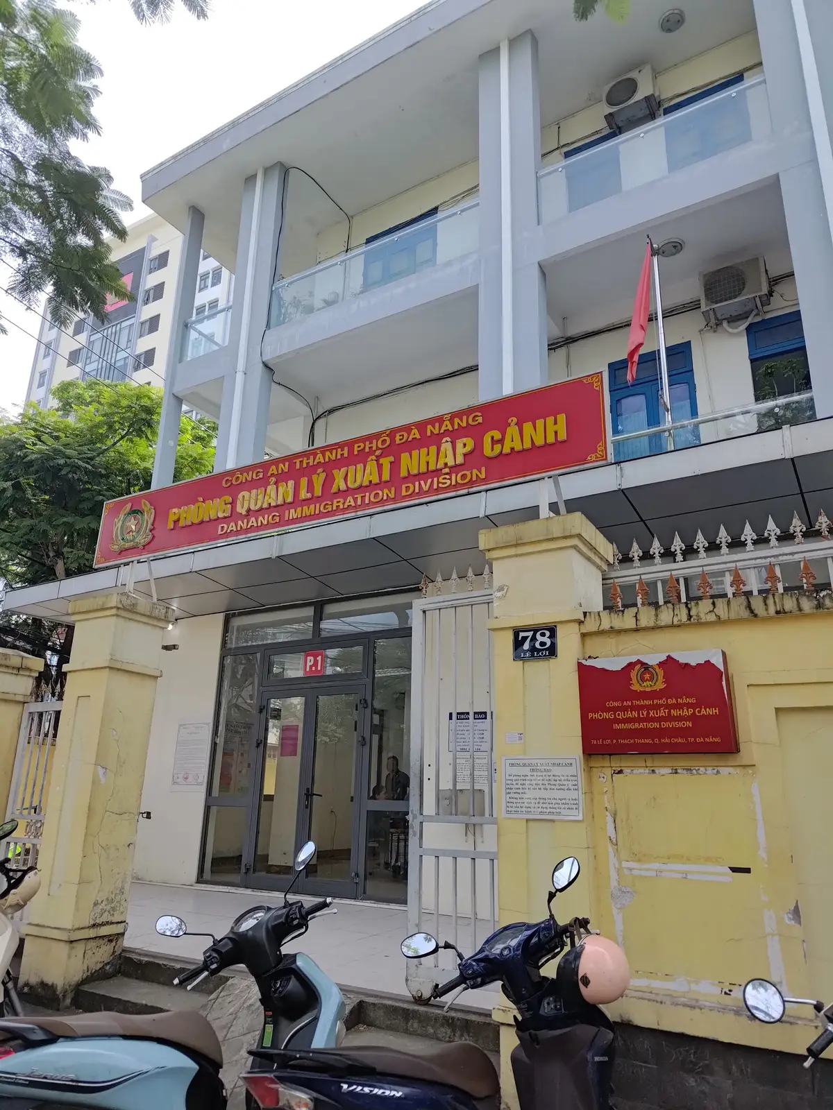 Danang Immigration Division이라고 쓴 붉은 간판이 유리 출입문과 번지 표지판 위에 달린 3층 노란 건물이에요.