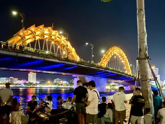 Dragon Bridge lit up at night over the Han River, crowds on the bank