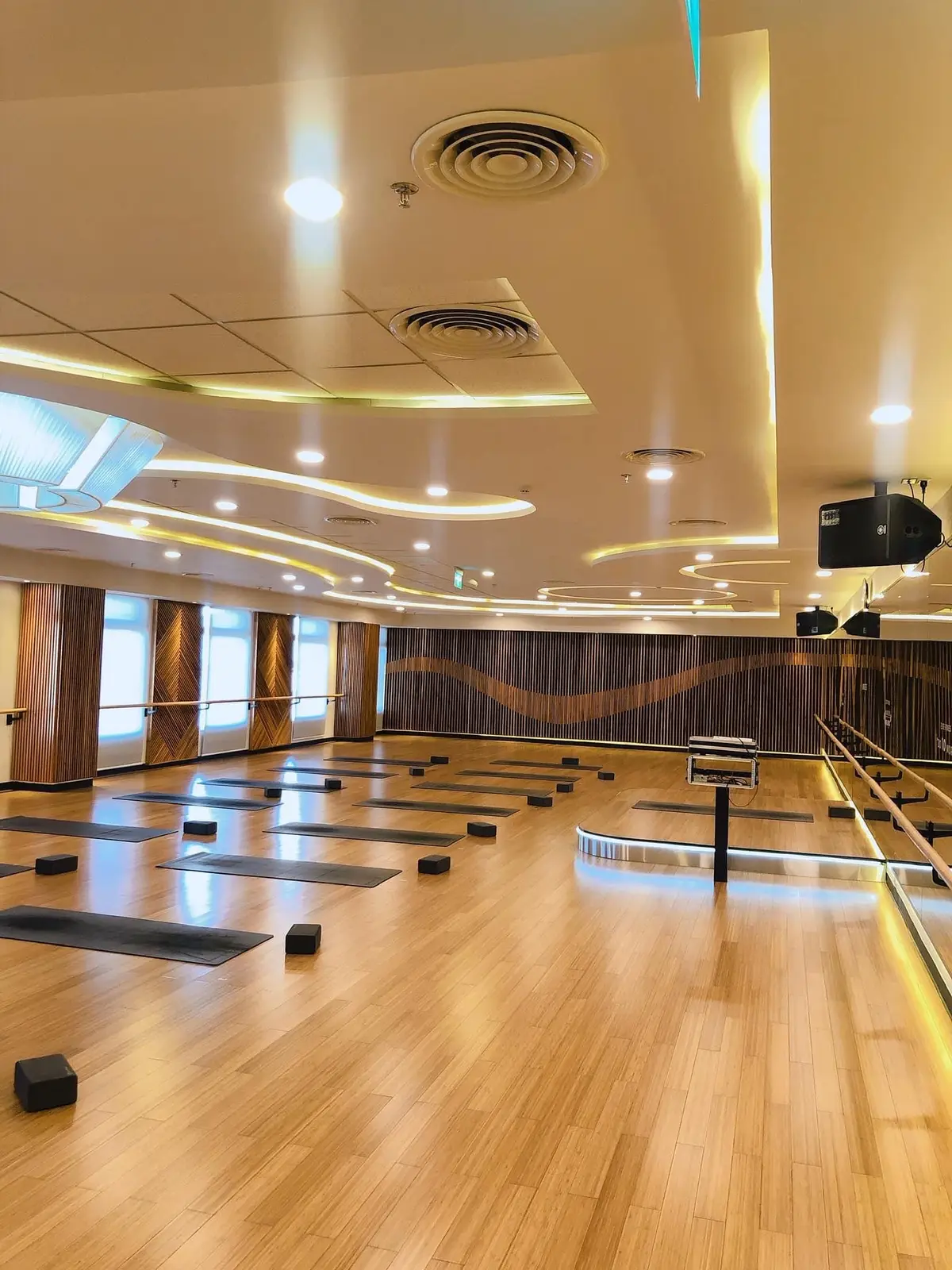 Empty wooden-floored studio room with mirrors and soft ceiling lighting