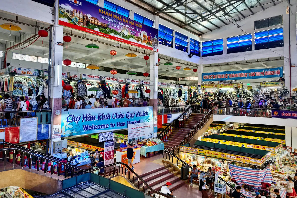 Inside Han Market, looking across the ground floor stalls to a staircase and a welcome banner, with the upper floor gallery above.