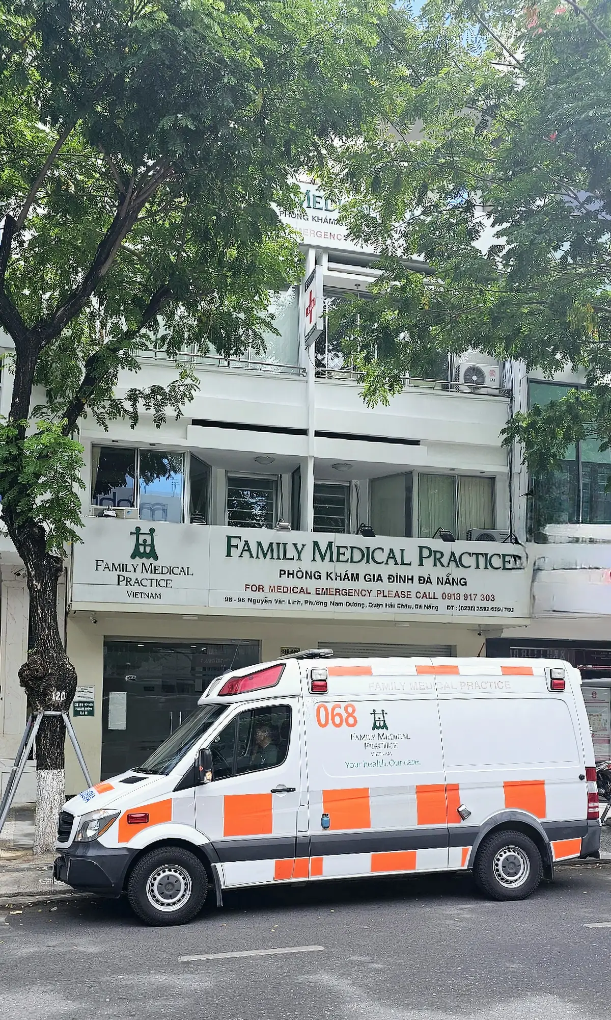 간판이 달린 여러 층 높이의 Family Medical Practice 정면과 길가에 세워 둔 구급차.