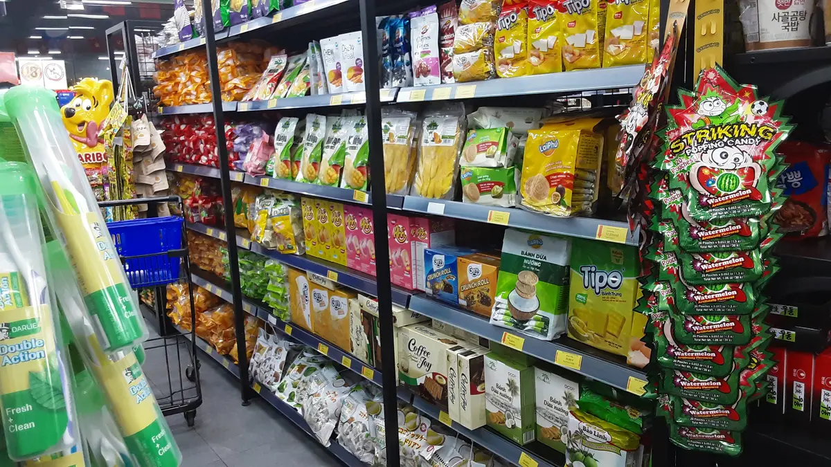 Narrow aisle with metal shelves packed with Korean snacks and groceries