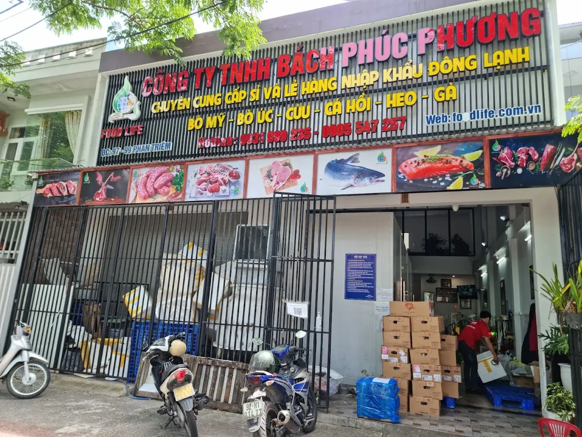 Narrow shop front with a large sign for imported frozen food and stacked boxes outside