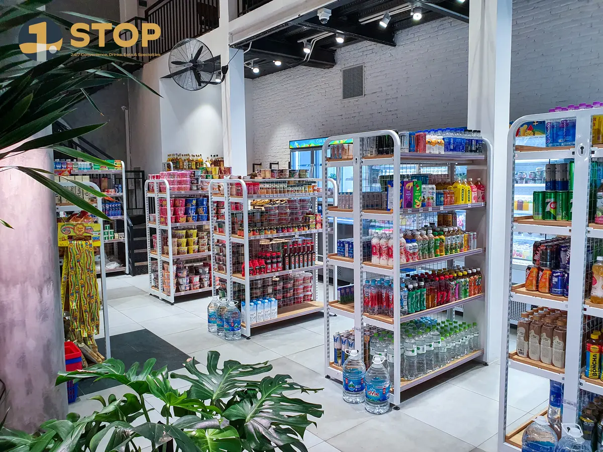 Bright convenience store interior with freestanding shelves of drinks and snacks among plants