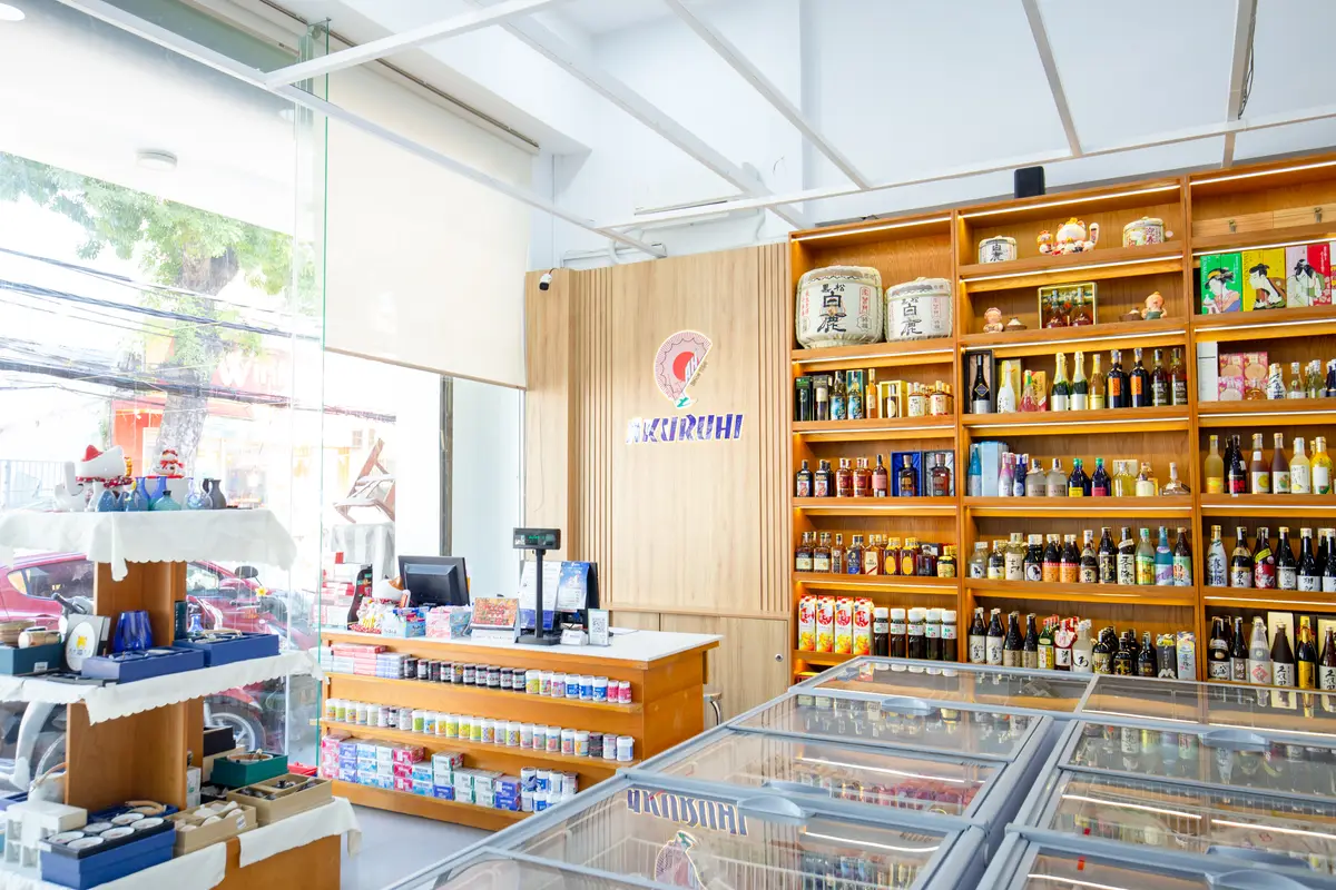 Wooden shelves stocked with Japanese sauces and condiments beside a freezer and checkout counter