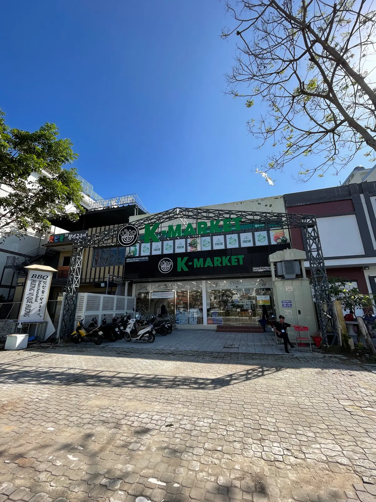 Low building with a green K-Market sign and a paved yard in front