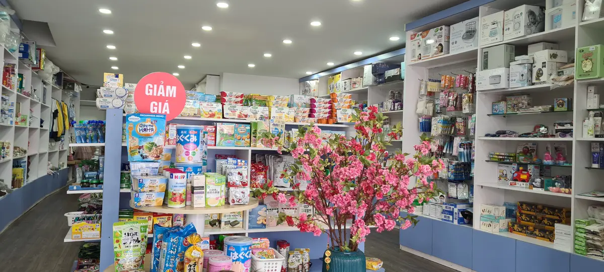 Bright shop interior with shelves of imported baby and food products and a flowering display
