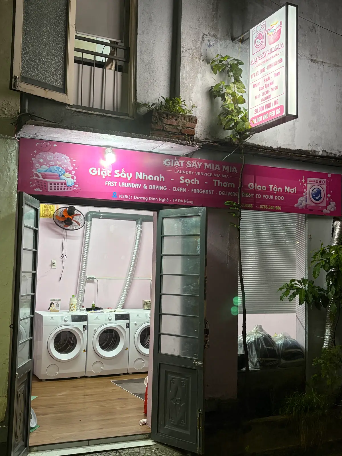Pink-signed laundry shop with three front-loading washing machines visible inside
