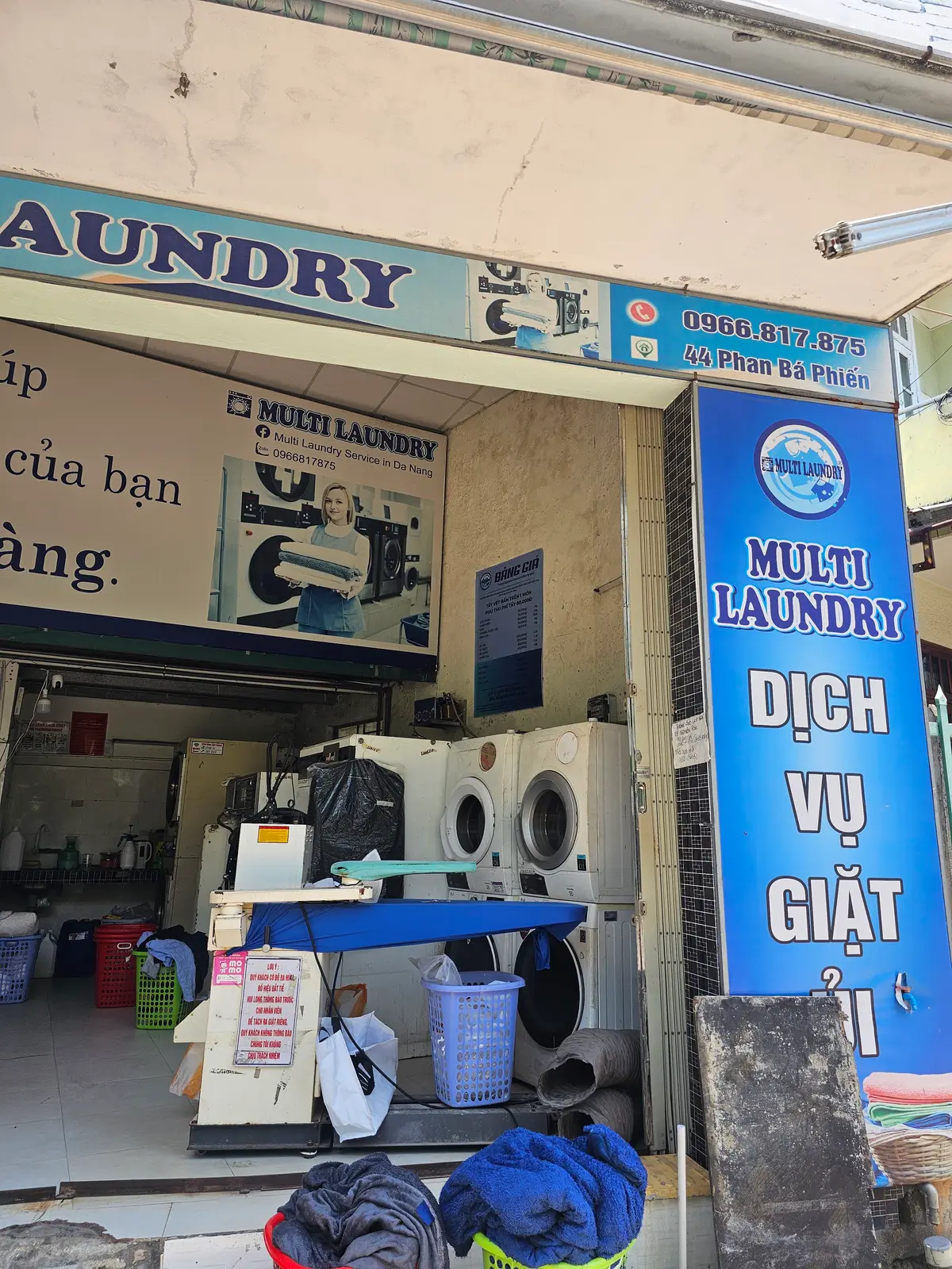 Small laundry shop with washing machines inside and a blue Multi Laundry sign by the door