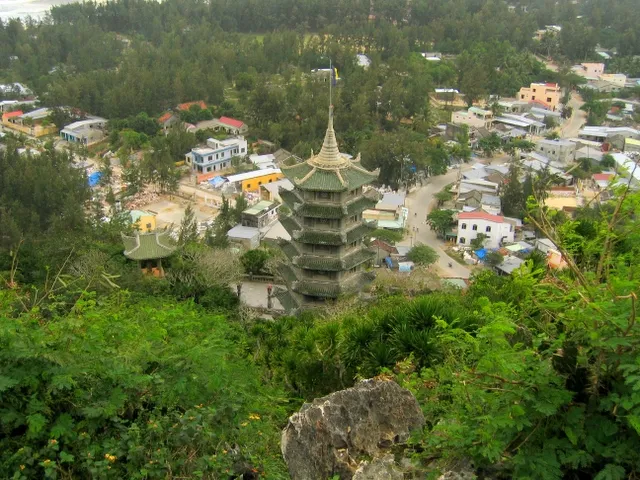 The green-roofed, multi-storey Xá Lợi tower seen from above on Thủy Sơn, with trees and the houses of the village below.