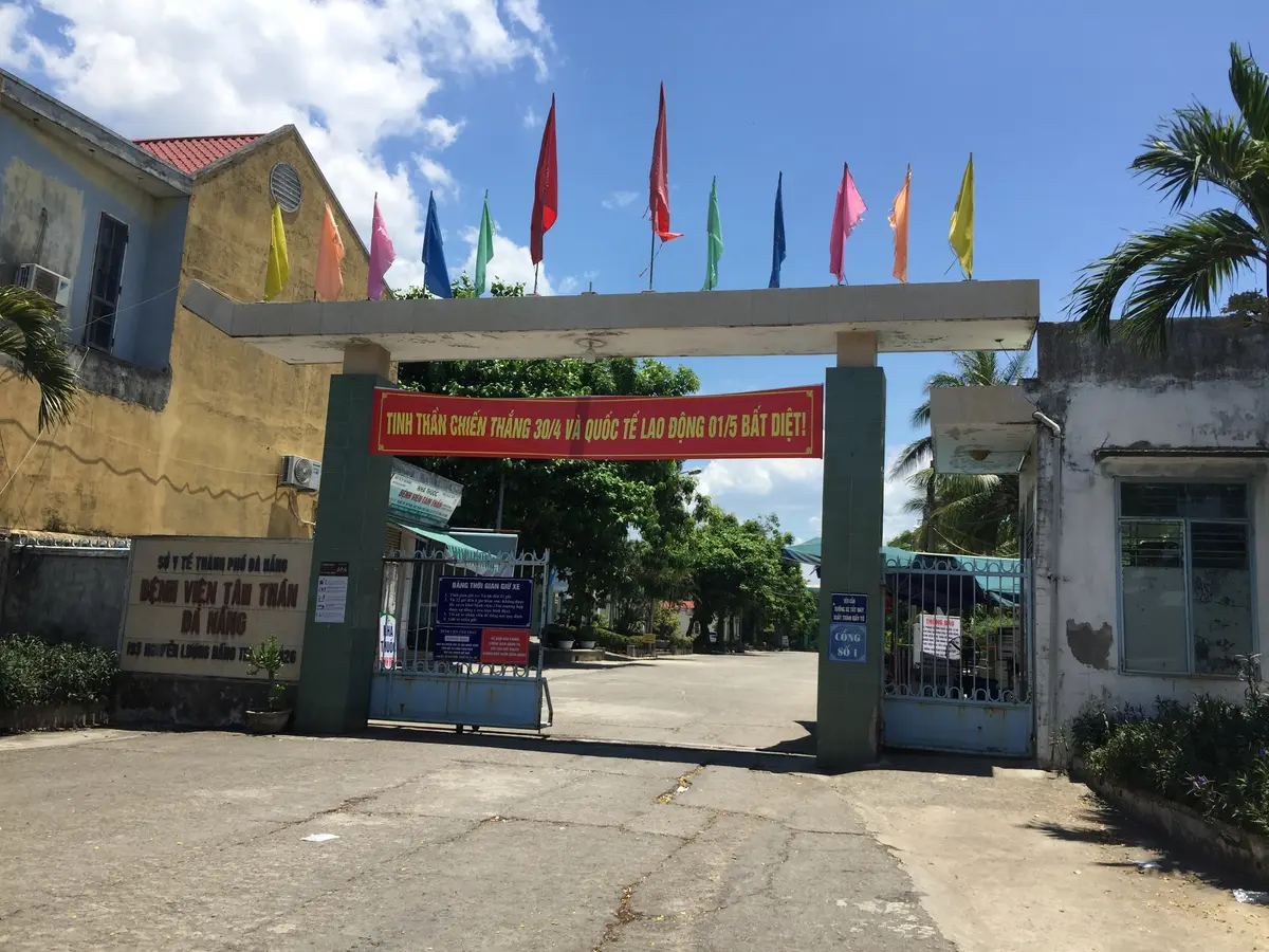 Da Nang Psychiatric Hospitalの門。病院名の看板が赤い横断幕の横にあり、入口の上にカラフルな旗が掛かっています。