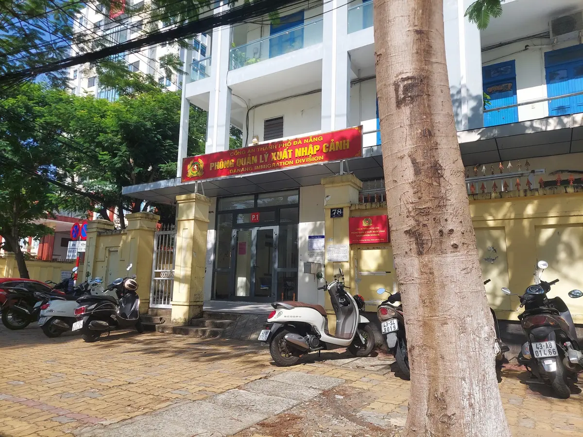 ガラスのドアの上に「Danang Immigration Division」と書かれた赤い看板があり、手前にバイクが停まっている