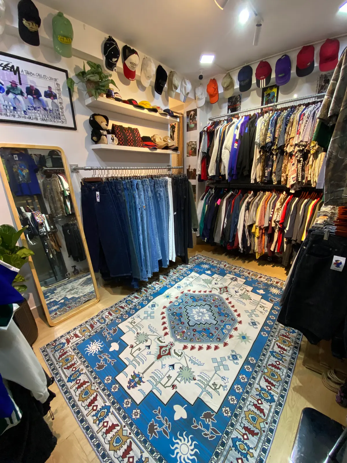A mirror, a rail of jeans and racks of jackets around a blue rug inside RMD Vintage Clothing Danang 2.