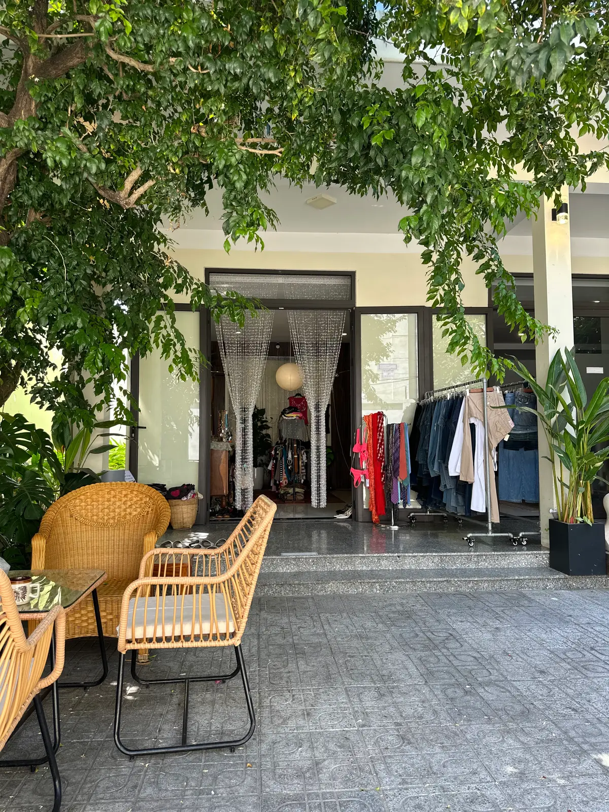 An Haiのヴィンテージ店の開けた店先:外に籐の椅子と鉢植えがあり、ビーズのカーテンの奥に服のラックが見える。