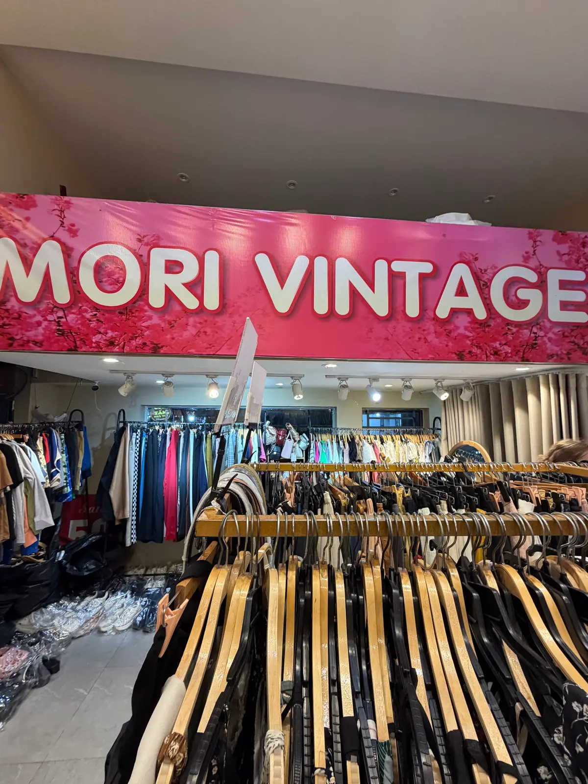 Inside Mori Vintage: long rails of second-hand jackets and shirts under a pink Mori Vintage sign.