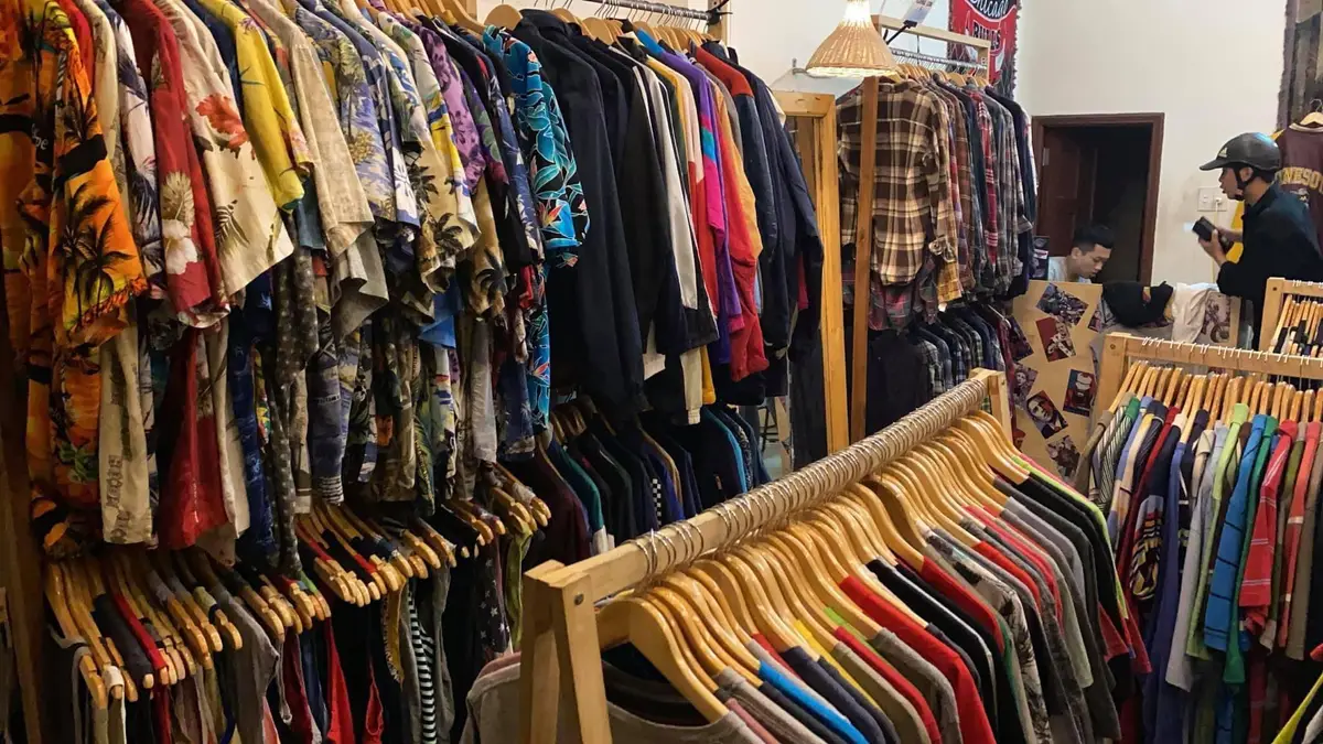 Wooden rails packed with second-hand patterned shirts and T-shirts inside Bo Vintage.