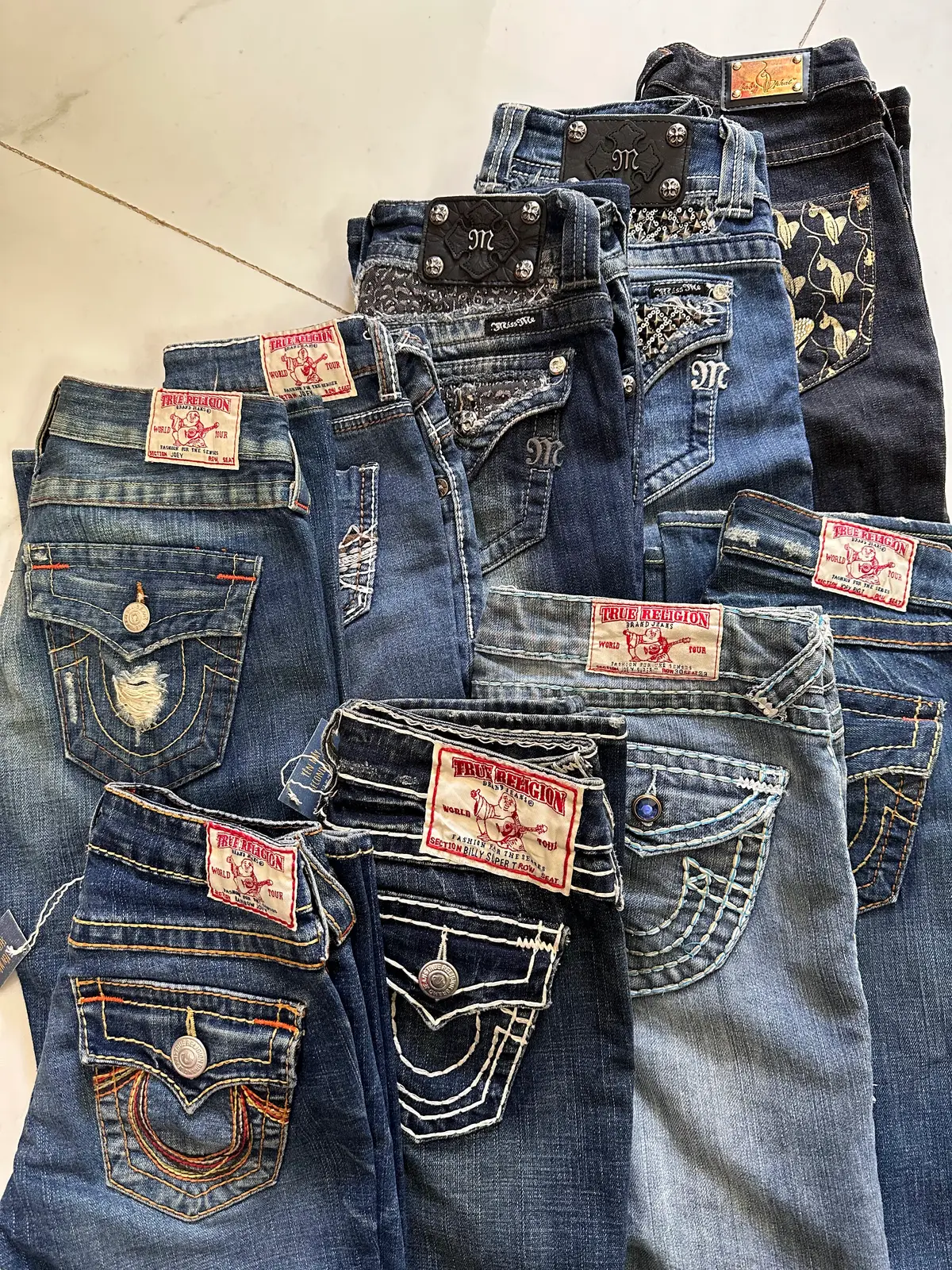 A pile of second-hand designer jeans with their leather back labels showing, in the An Hai shop.